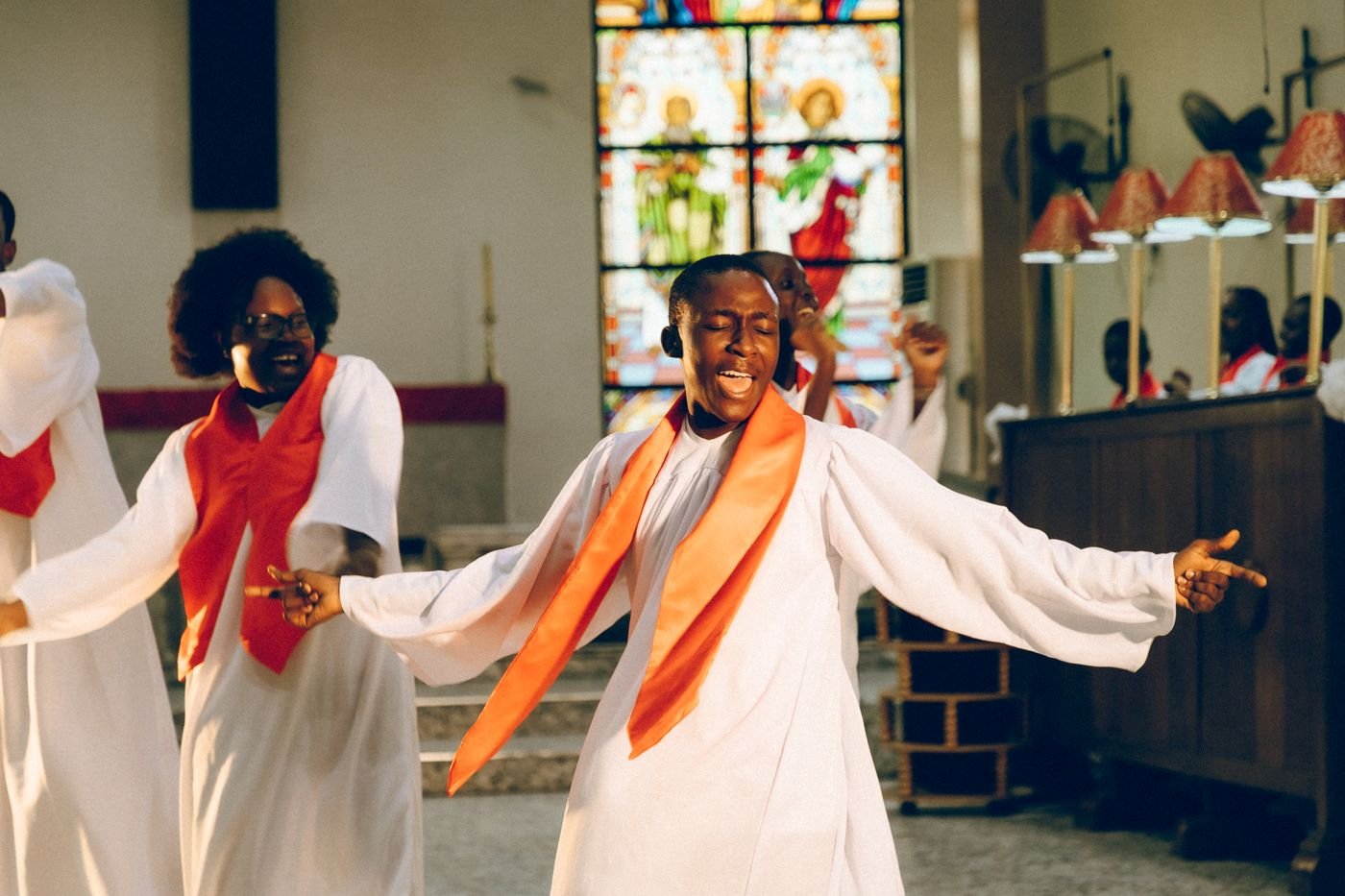 A church choir in white robes singing and dancing